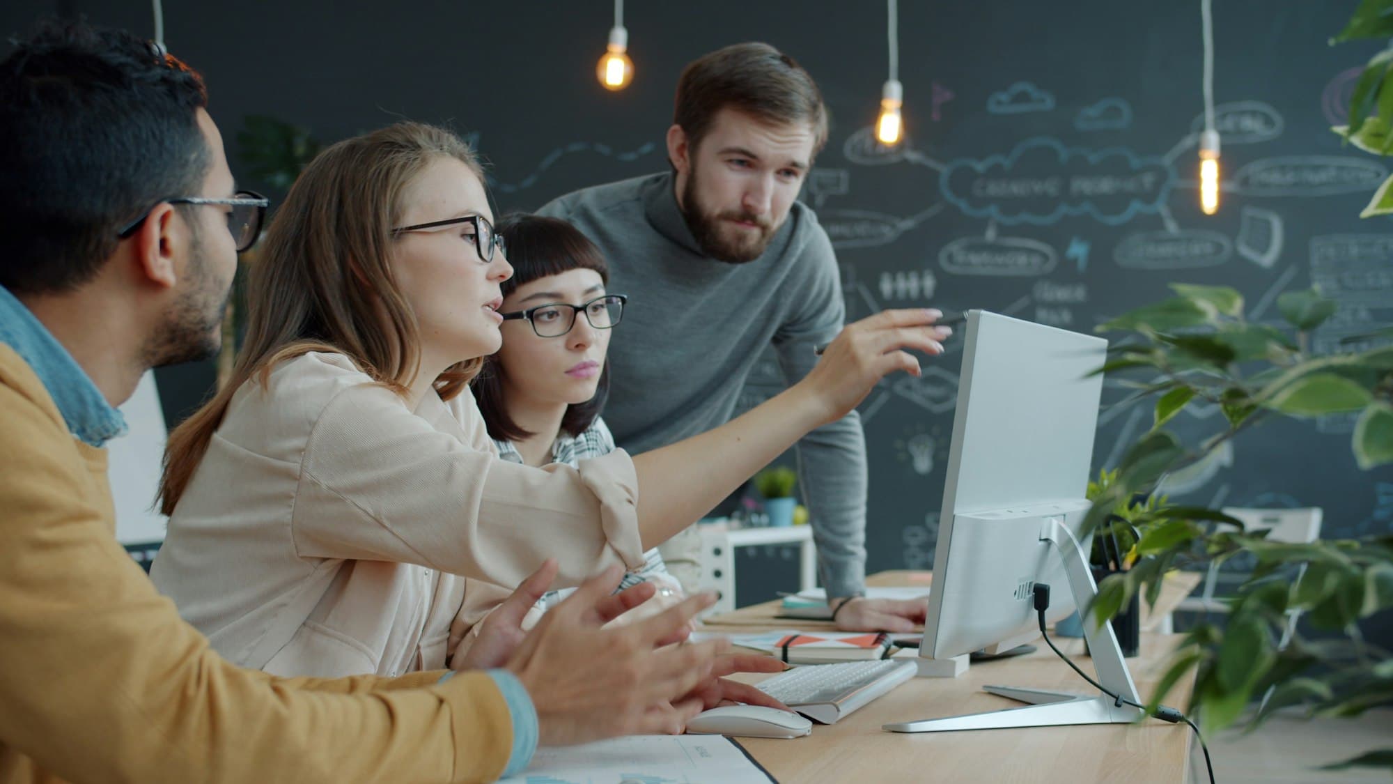 A coaching team collaborating around a shared screen
